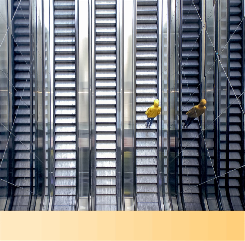 Person in a yellow hooded jacket rides an escalator