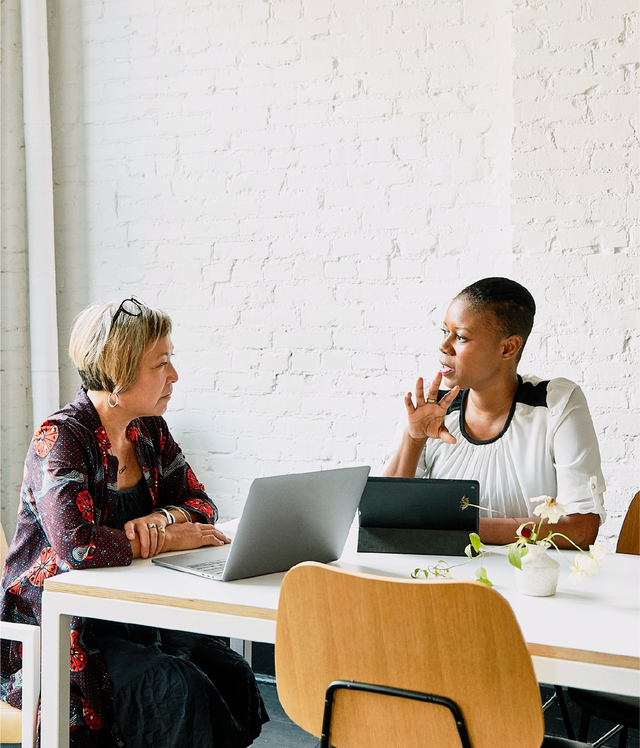Two women discuss business in a conference room.