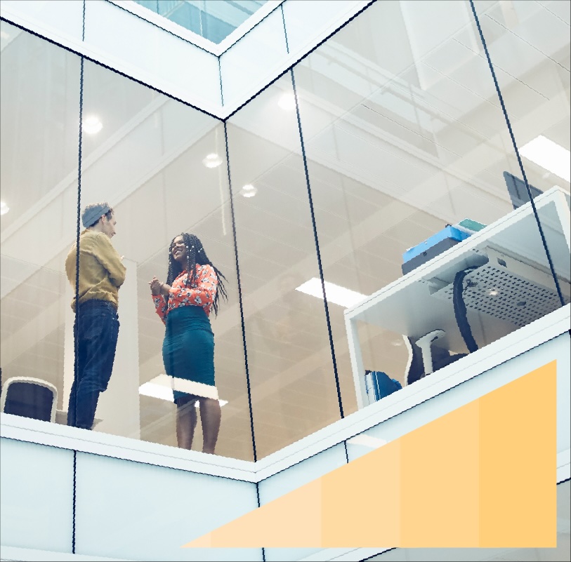 Low-angle photo of two colleagues talking in their office through a glass wall. 