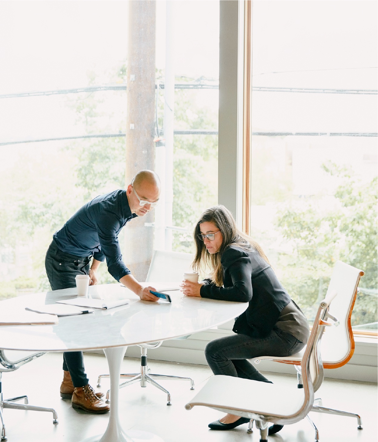 Two colleagues discuss a work project with their mobile phone.